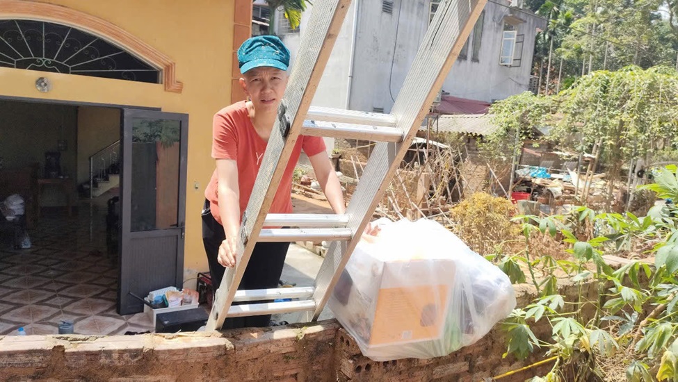 Chị Đỗ Quỳnh Giang, TP Yên Bái phải trèo qua thang để nhận quà. Chị Giang vừa phẫu thuật ung thư, với 2 con trai nhỏ, trong đó một bé mắc bệnh hiểm nghèo, nhà chị sập hoàn toàn, đang phải ở nhờ nhà mẹ đẻ. 